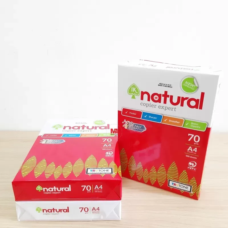 Các chồng giấy A4 IK Natural 70gsm với bao bì màu đỏ trắng đặc trưng, đặt trên nền gỗ sáng