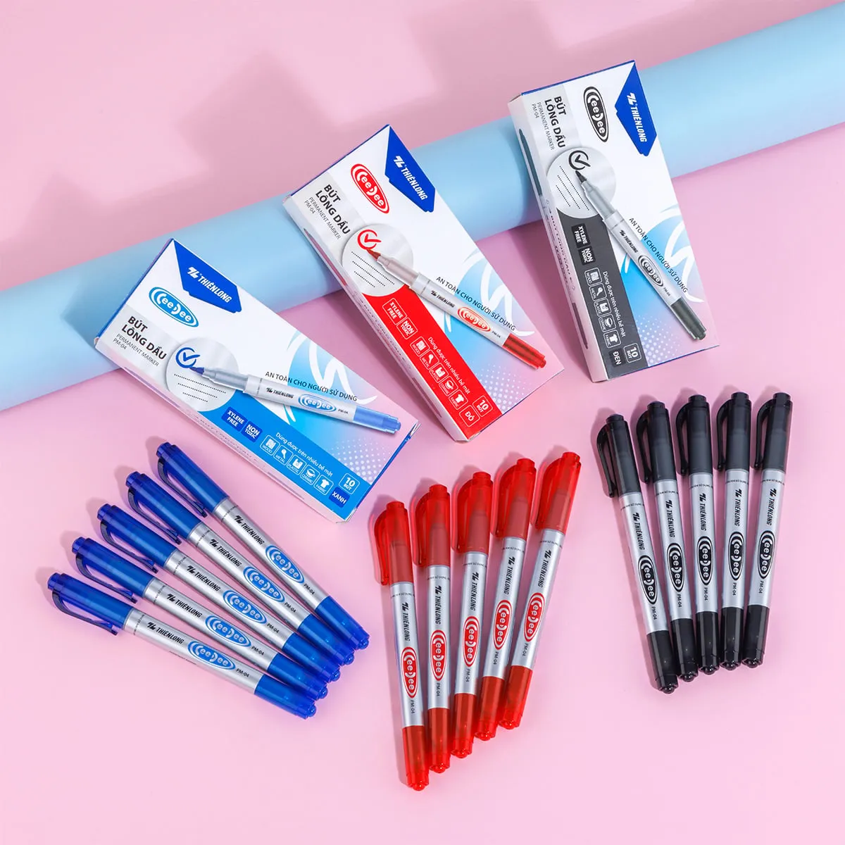 bút lông dầu thiên long PM-04 2 đầu với các hộp và thân bút màu xanh, đỏ, đen được sắp xếp trên nền hồng.