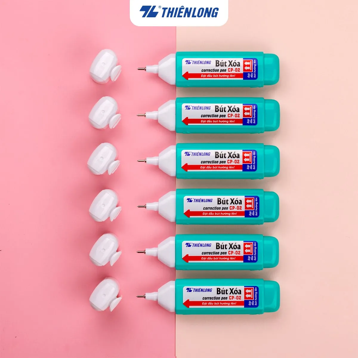 Sáu cây bút xóa Thiên Long CP-02 màu xanh ngọc đặt song song bên cạnh nắp đậy trên nền hồng và kem