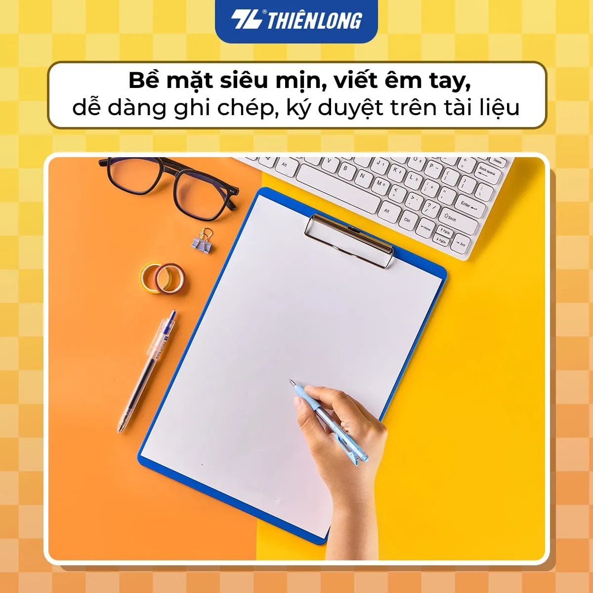 Tay người đang viết lên bìa trình ký đơn Flexoffice trên bàn làm việc có máy tính và phụ kiện văn phòng.