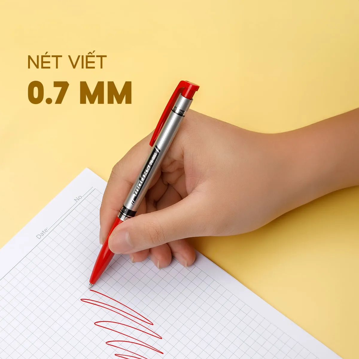 Bàn tay đang dùng bút bi Flexoffice FO-024 mực đỏ với nét viết 0.7mm để vẽ lên giấy kẻ ô vuông trên nền vàng