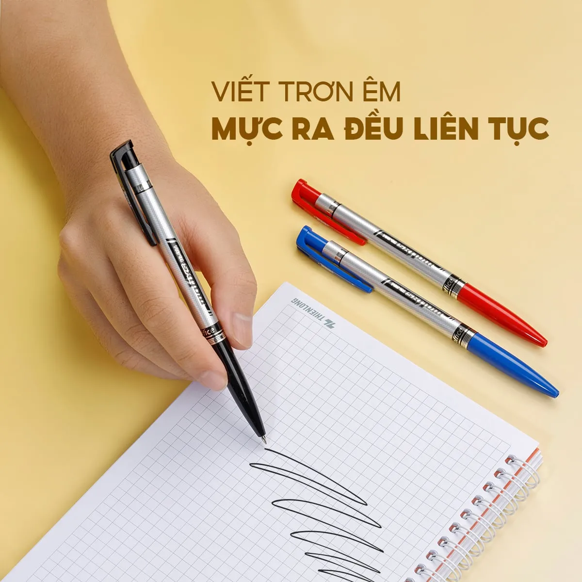 Tay người đang cầm bút bi flexoffice FO-024 viết trên giấy, bên cạnh là hai cây bút khác màu đỏ và xanh