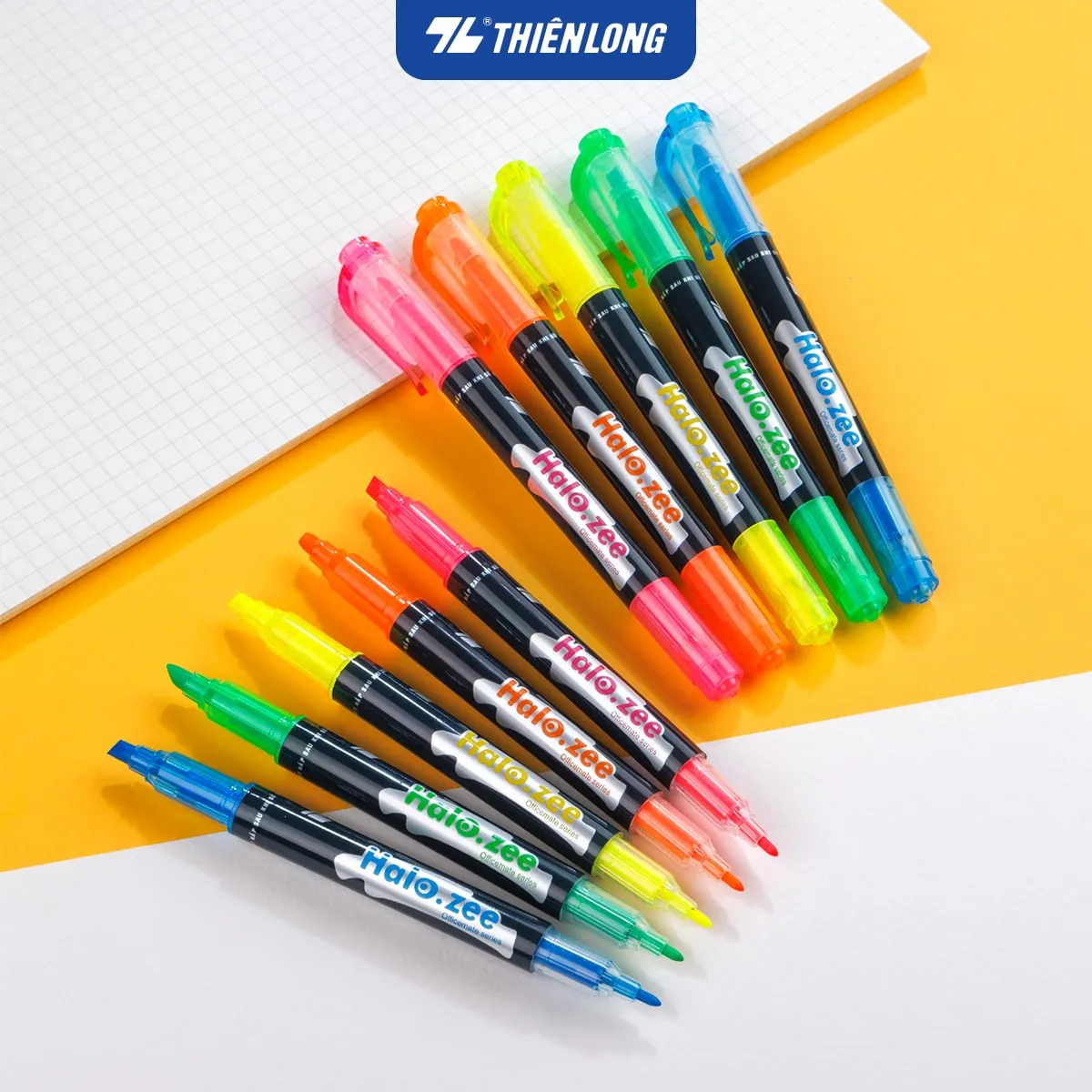 Bộ bút dạ quang Thiên Long Halo.zee nhiều màu sắc tươi sáng đặt trên nền giấy kẻ ô và mặt bàn vàng