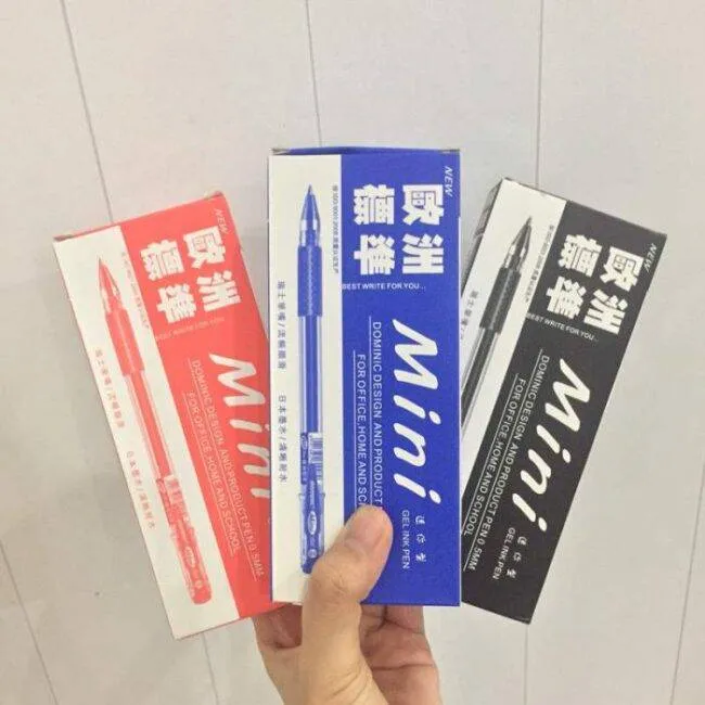 Bàn tay đang cầm ba hộp bút gel mini với các màu vỏ đỏ, xanh và đen khác nhau.