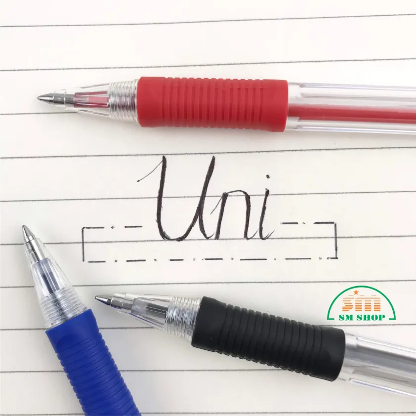 Các loại bút bi uni với phần đệm tay màu sắc đặt trên nền giấy kẻ ô có chữ viết tay