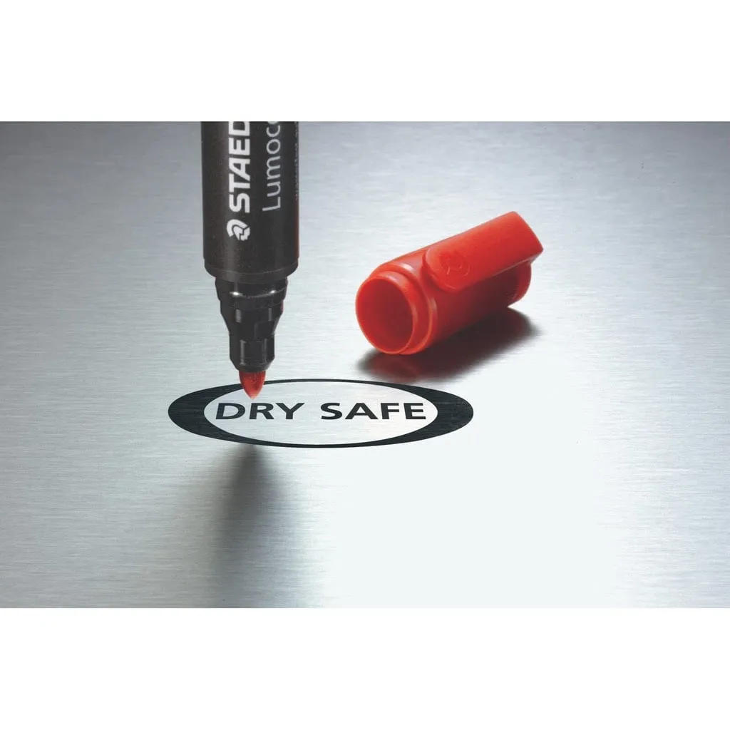 Đầu ngòi của bút dạ dầu Staedtler viết chữ Dry Safe trên bề mặt kim loại với nắp đỏ đặt bên cạnh