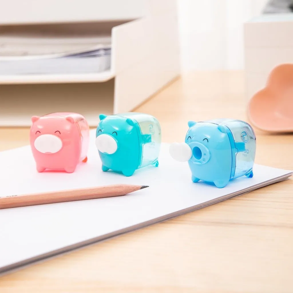Ba chiếc gọt chì Deli hình chú heo dễ thương với ba màu sắc khác nhau đặt trên mặt bàn