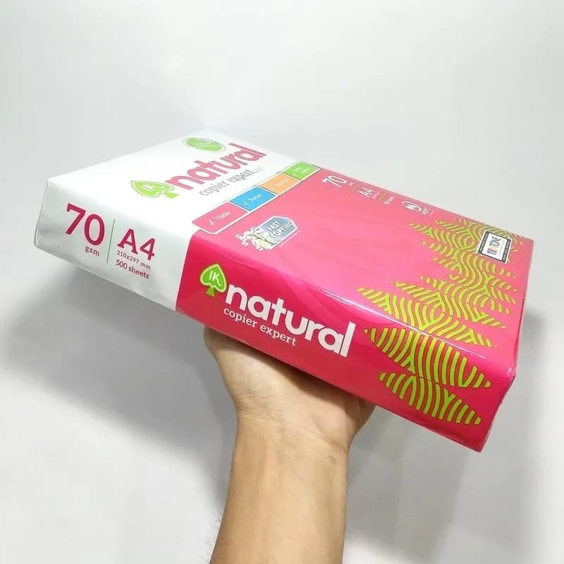 Giấy a4 ik natural định lượng 70gsm với bao bì màu hồng nổi bật được cầm trên tay