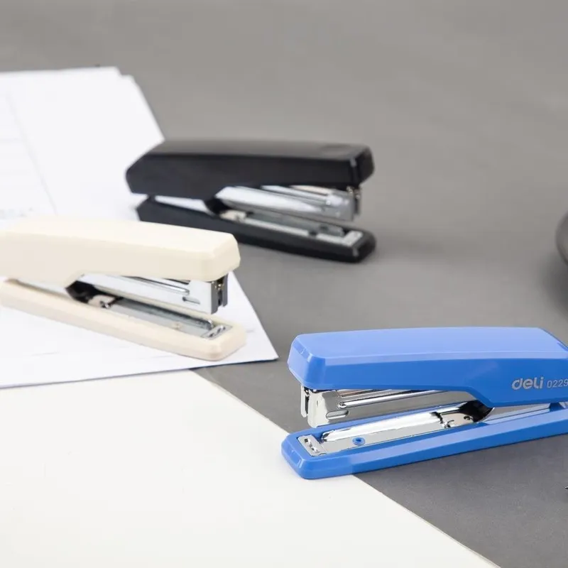 dập ghim deli 0229 cỡ số 10 nhiều màu xanh, trắng và đen đặt trên mặt bàn làm việc.